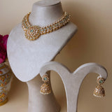 Gold colored jewelry set with light green stones and jhumka earrings